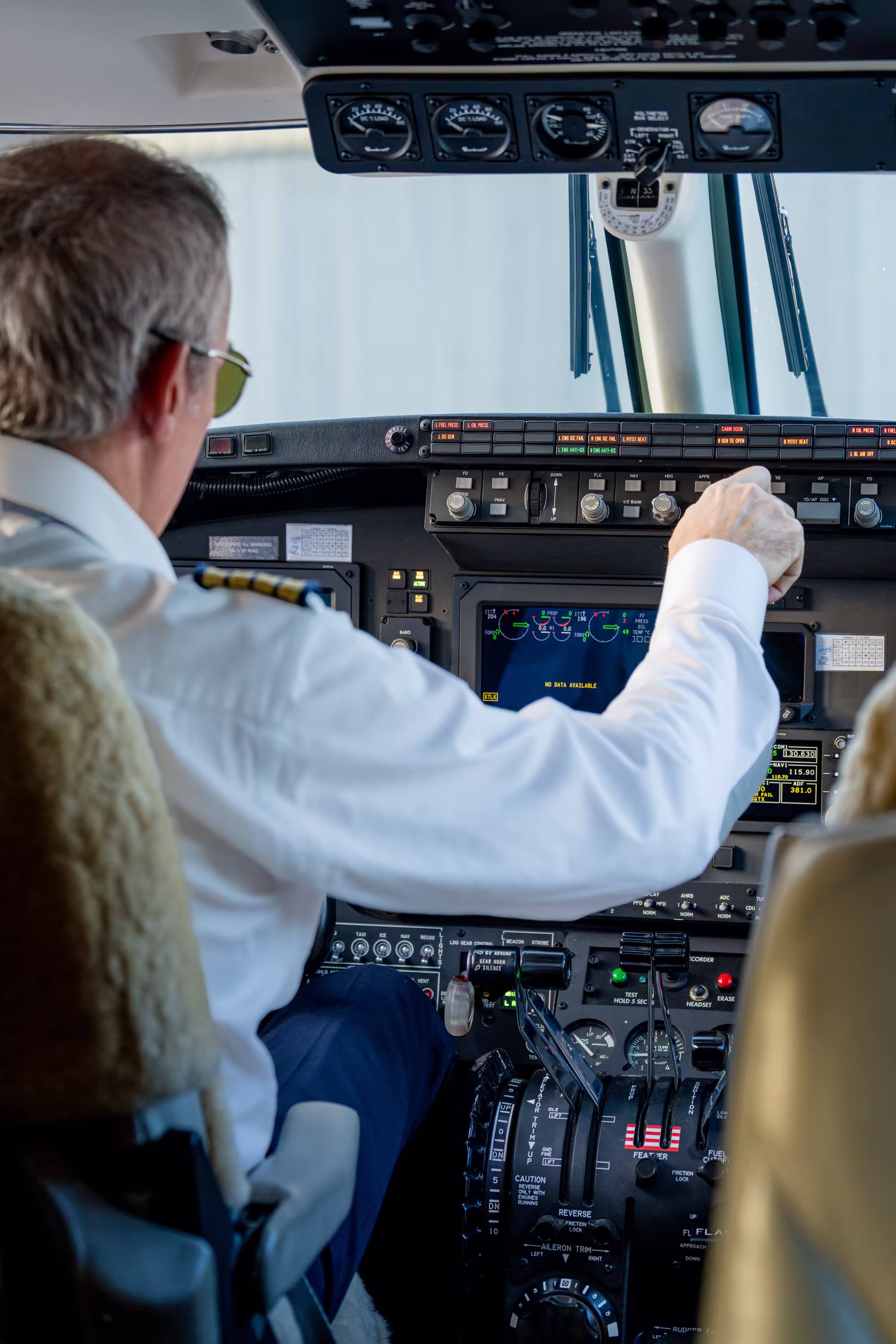 Le pilote: Jean-Luc Adam au commande de l'avion Chronos. Vu de dos avec le tableau de bord en fond.